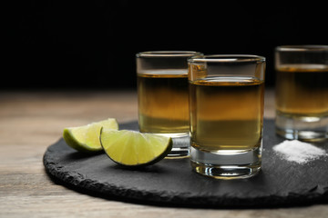 Mexican Tequila shots, lime slices and salt on wooden table