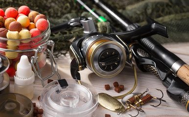 Fishing rods and spinnings in the composition with accessories for fishing on the old background on the table