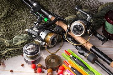 Fishing rods and spinnings in the composition with accessories for fishing on the old background on the table