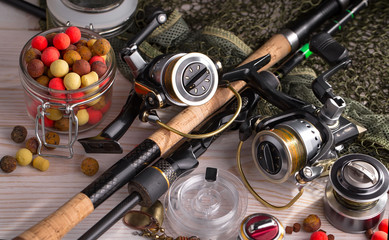 Fishing rods and spinnings in the composition with accessories for fishing on the old background on...