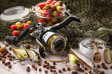 Fishing rods and spinnings in the composition with accessories for fishing on the old background on the table