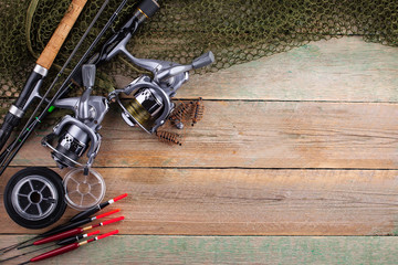 Fishing rods and spinnings in the composition with accessories for fishing on the old background on...