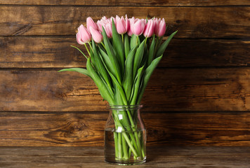 Beautiful pink spring tulips in vase on wooden table