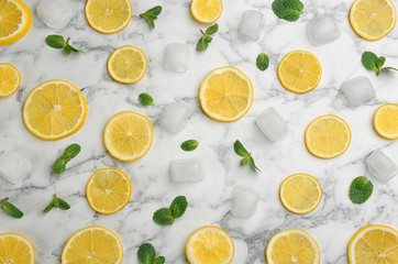 Lemonade layout with juicy lemon slices, mint and ice cubes on white marble table, top view