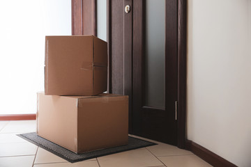 Cardboard boxes on rug near door. Parcel delivery service