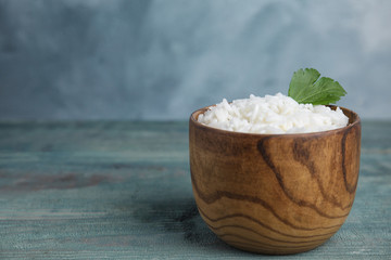 Bowl with tasty cooked rice on light blue wooden table. Space for text