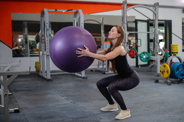 Fototapeta na wymiar Sporty young woman in gym training with fitness ball. Sport and fitness lifestyle.