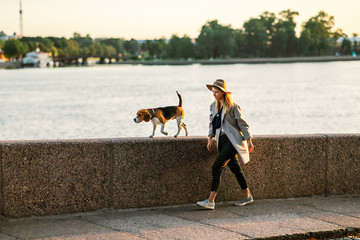 Young female strolling in promenade with Beagle dog