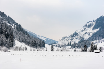 Winter mountain landscape in the Alps. The building, trees and mountains covered with snow.