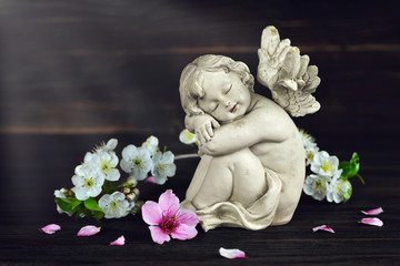 Guardian angel and spring flowers on dark wooden background