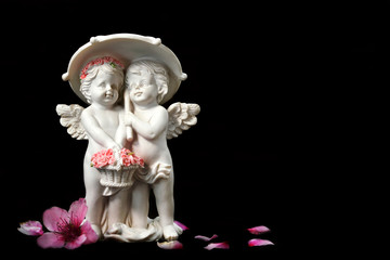 Two angels figurine isolated on black background with copy space. Love concept.