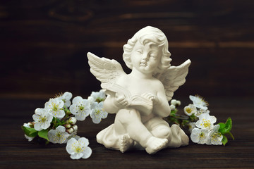 Guardian angel and spring flowers on wooden background