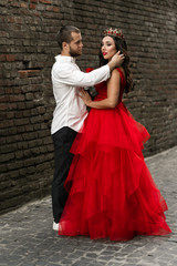 Beautiful romantic couple. Attractive young woman in red dress and crown with handsome man in white shirt are in love. Happy Saint Valentine's Day. Pregnant and wedding concept.