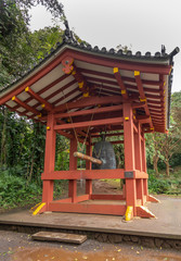 Kaneohe, Oahu, Hawaii, USA. - January 11, 2020: Red pavilion for giant sacred bell in garden of Byodo-In Buddhist temple. Greeen foliage background.