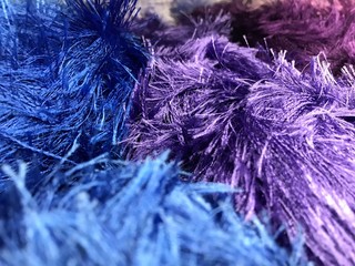 Texture of different sharpness from fluffy bright yarn of blue and lilac shades. Mobile photo with store lighting.