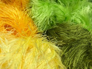 Texture of different sharpness from fluffy bright yarn of yellow and green shades. Mobile photo with store lighting.