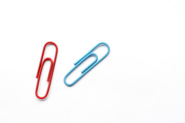 Pair of paper clips, red and blue, on white background