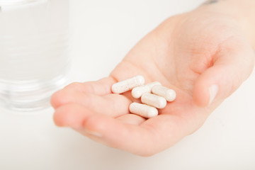 Saspirella supplements or vitamin capsule in female hands with glass of water