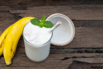 Coconut blend banana milk smoothie drink fresh cocktail shake milkshake vanilla juice fruit beverage food healthy the taste yummy In glass on wooden background.