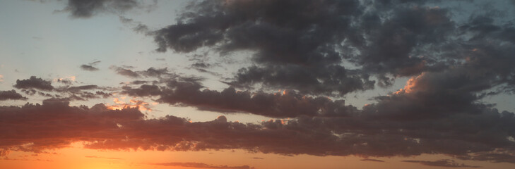 panoramic landscape showing the fiery burning colors of the sun setting in the clouds after a hot summers day in Australia