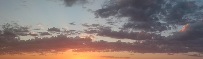 panoramic landscape showing the fiery burning colors of the sun setting in the clouds after a hot summers day in Australia