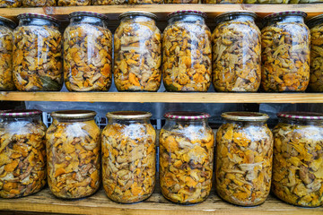 Tasty brown pickled mushrooms in a glass jar close up, homemade pickles