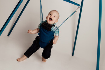 Jolly Baby boy bouncing in jumper  / jumping stand.