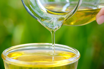 Pouring olive oil in the a glass bowl at stone kitchen and inside green garden view. Prepare for cooking concept. Healthcare and Beauty Concept.