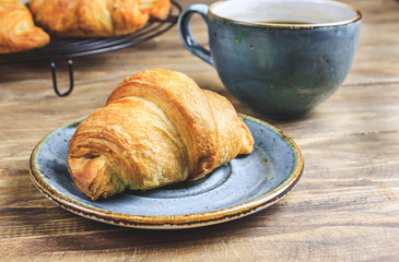 Coffee and croissant on rustic wooden table. French breakfast. Top view. Flat lay. Copy space.