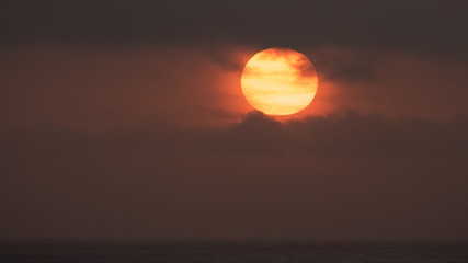 Sunrise over the Pacific Ocean with heavy smog and smoke