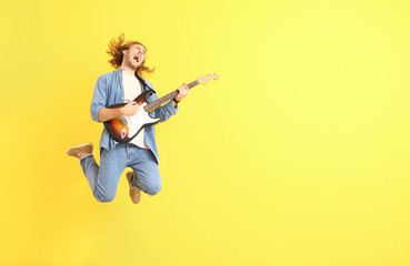 Jumping man with guitar on color background