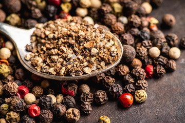 Mixed peppercorns on the rustic background. Selective focus. Shallow depth of field.