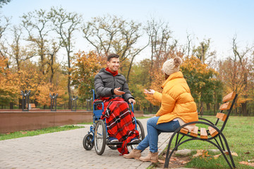 Handicapped young man and his wife in autumn park