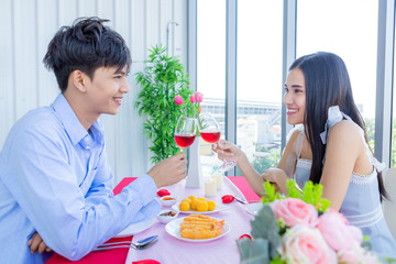 Valentine's day concept,Happy Asian Young sweet couple having romantic the Lunch with clinking toasting wine glasses at the restaurant background.