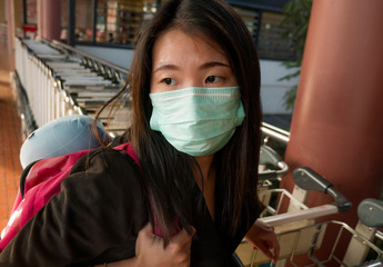 young beautiful and attractive Asian Chinese student at airport wearing protective facial mask...