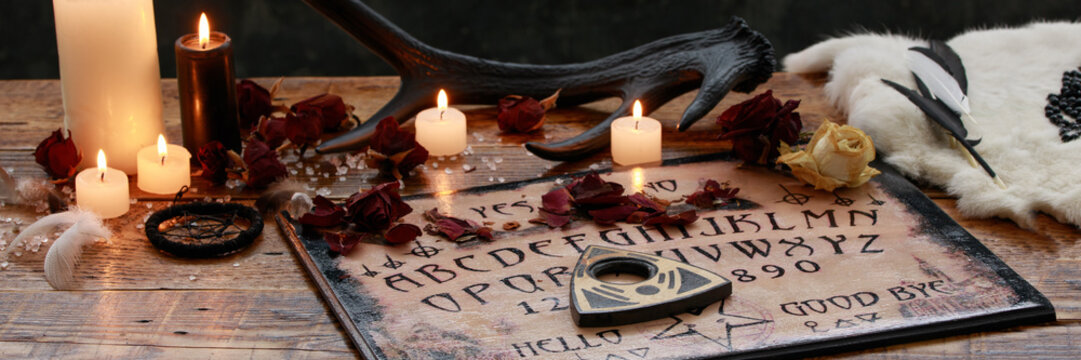 Mystic ritual with Ouija and candles. Devil's board concept, black magic or fortune telling rite with occult and esoteric symbols.