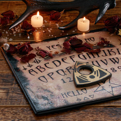 Mystic ritual with Ouija and candles. Devil's board concept, black magic or fortune telling rite...