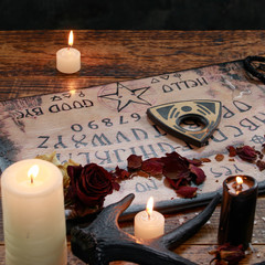 Mystic ritual with Ouija and candles. Devil's board concept, black magic or fortune telling rite...