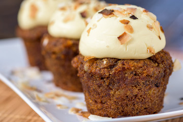 Three Vegan Apple, Walnut, Sultana and Coconut cupcakes, on a white plate.