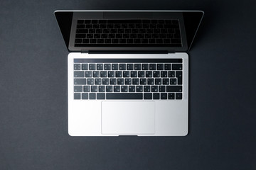 Top view of a modern compact laptop on a dark background. High technology. The laptop screen is open. The concept of a modern gadget. Freelancer's workplace. Black background