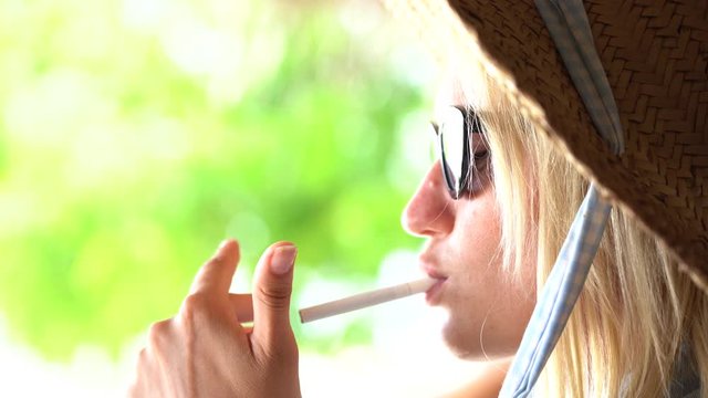 The young woman who is smoking a cigarette and carrying away a smoke in air, close up