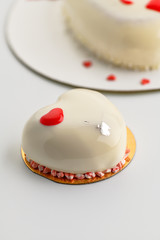 Cake. One small mousse  white cake  in heart shape  on a white background. Vertical photo