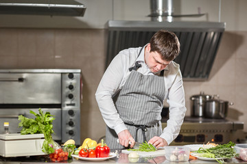 Young chef cutting beet on a white cutting board closeup. Cooking in a restaurant kitchen