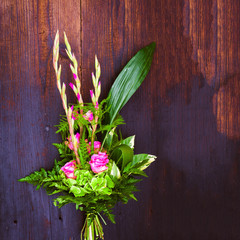 Bouquet composition with pink rose and gladiolus on blue wooden background