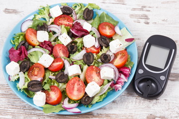 Glucometer for checking sugar level and fresh greek salad. Diabetes and healthy lifestyles