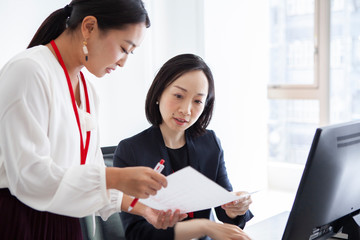 資料を確認し合う女性社員たち