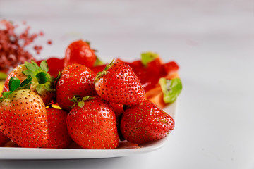Fresh organic strawberries with flowers on white background.
