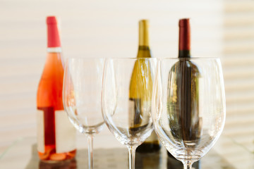 Wine tasting set in the light airy environment. Custom wine tasting concept. Glasses of wine and bottles on the glass table and light background.