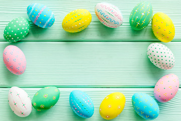 Colorful Easter eggs frame on green wooden background top-down copy space
