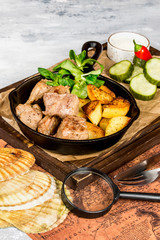 Potato with meat in a pan and fresh vegetables